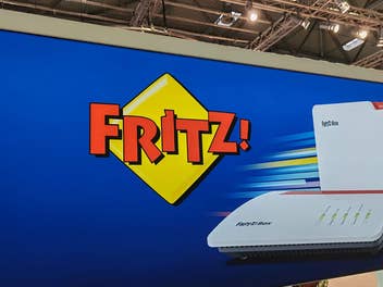 Das Fritz-Logo von AVM mit Routern auf einer blauen Wand.