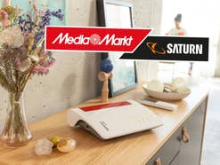 FritzBox Router 6670 Cable auf einem Tisch, daneben das Logo von MediaMarkt