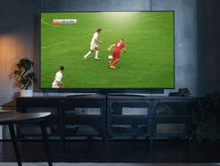 Ein Fußballspiel wird auf einem Fernseher übertragen, der in einem Wohnzimmer steht