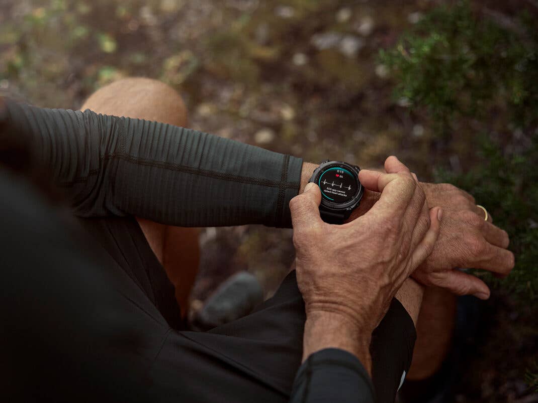 Eine Person, die eine Garmin-Smartwatch in einer Outdoor-Umgebung an ihrem Handgelenk überprüft.