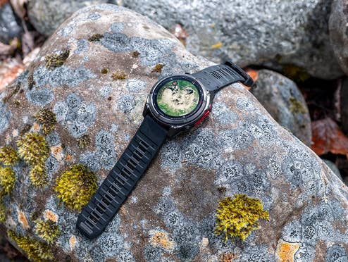 Eine Garmin-Uhr, die auf einem moosigen Stein in der Natur liegt.