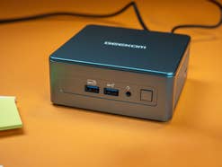 Geekom Mini IT13 auf einem Schreibtisch mit zwei offenen Anschlüssen und Ein-/Ausschalter auf der Vorderseite.