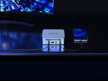 Geekom XT13 Pro mit einem Smartphone auf einem Schreibtisch.