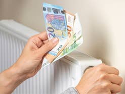 Geld wird vor eine Heizung gehalten