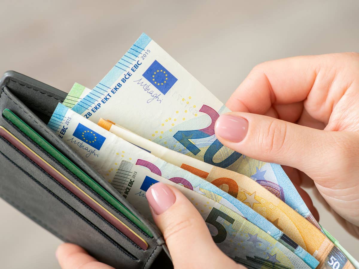 Person steckt Geldscheine in einen Geldbeutel