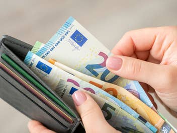 Person steckt Geldscheine in einen Geldbeutel