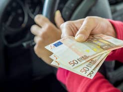 Mann hält Geldscheine in einem Auto