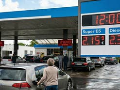 Tankstellensituation mit mehreren Autos und Menschen