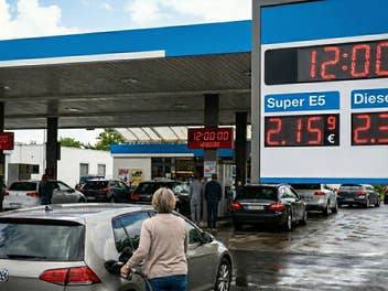 Tankstellensituation mit mehreren Autos und Menschen