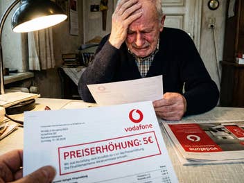 Ein Mann sitzt verzweifelt an seinem Tisch, im Vordergrund ein Preiserhöhungsschreiben