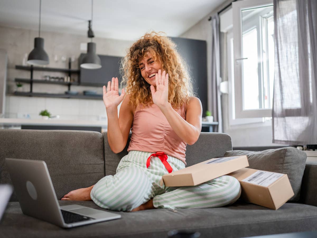 Frau sitzt mit Laptop auf einem Sofa