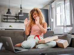 Frau sitzt mit Laptop auf einem Sofa