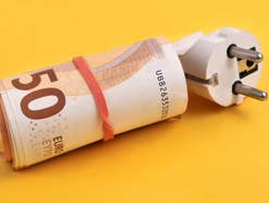 Gewaltige Unterschiede: Hier ist Strom besonders teuer 50-Euro-Scheine um einen Stromstecker.