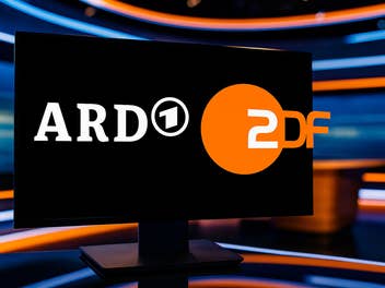 Logos von ARD und ZDF auf einem Monitor in einem TV-Studio.