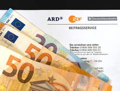Formular für den Beitragsservice von ARD und ZDF mit Geldscheinen, die den Rundfunkbeitrag (GEZ-Gebühr) finanzieren.