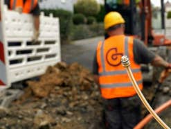 Ein Bauarbeiter steht in einem Kabelschacht. Im Vordergrund ist eine Glasfaser-Speedpipe zu sehen