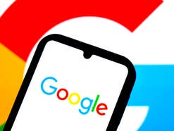 Google-Logo auf einem Smartphone mit einem Google-G im Hintergrund.