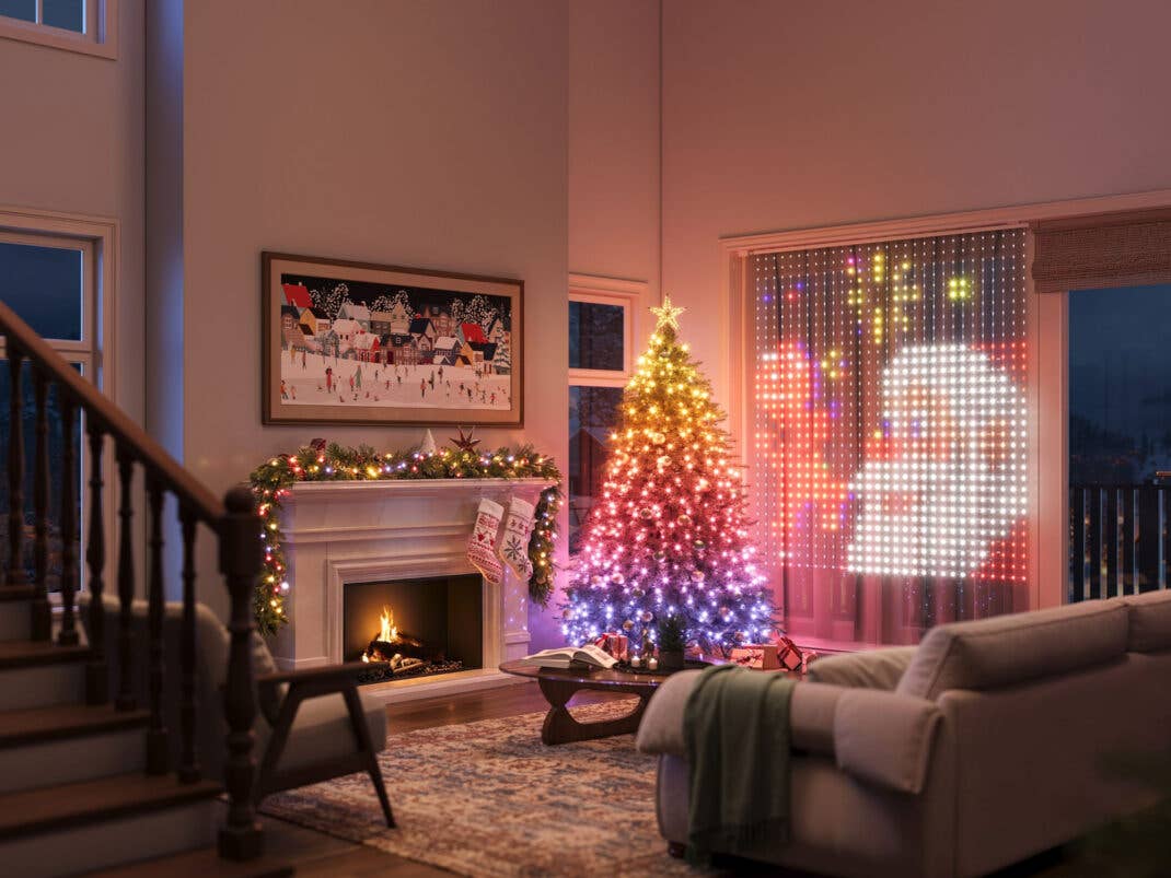 Ein weihnachtliches Wohnzimmer wird durch smarte Lichter beleuchtet. Weihnachtsbaum und Vorhänge leuchten Bund und in Motiven.