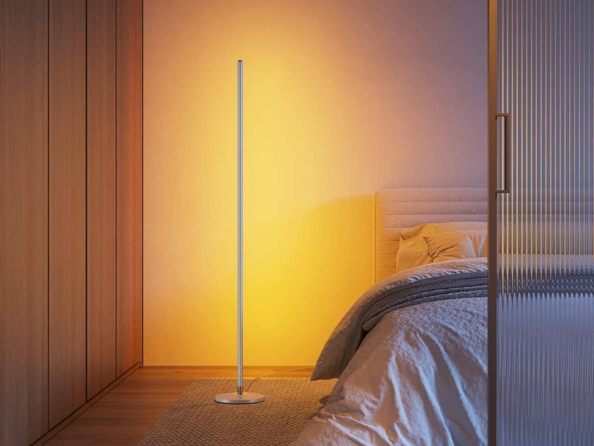 Eine Stehlamp steht neben einem Bett