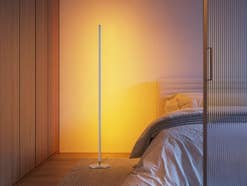 Eine Stehlamp steht neben einem Bett