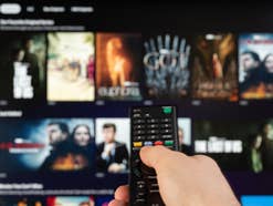 Hand mit Fernbedienung steuert Streaming-App