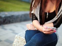 Eine Frau hält ein Handy in der Hand und liest eine Nachricht