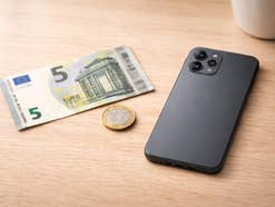 Handy neben einem 5-Euro-Schein und einer 1-Euro-Münze
