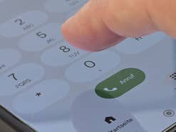 Ein Finger tippt auf der Telefontastatur eines Handys
