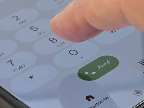 Ein Finger tippt auf der Telefontastatur eines Handys