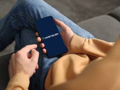 Eine Person hält ein Smartphone auf dem das Handyhelden-Logo zu sehen ist.