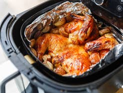 Heißluftfritteuse mit Hähnchen und Alufolie im Garkorb