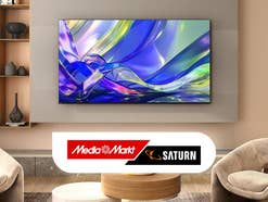Fernseher in einem beige eingerichteten Wohnzimmer. Darunter das MediaMarkt/Saturn-Logo