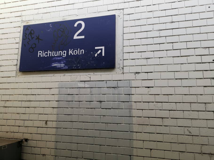 Schild am Bahnhof Brühl mit einer weißen Wand