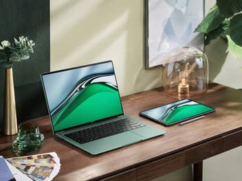 Das Notebook Huawei MateBook 14s in Grün auf einem Schreibtisch neben Pflanzen und anderen Utensilien.