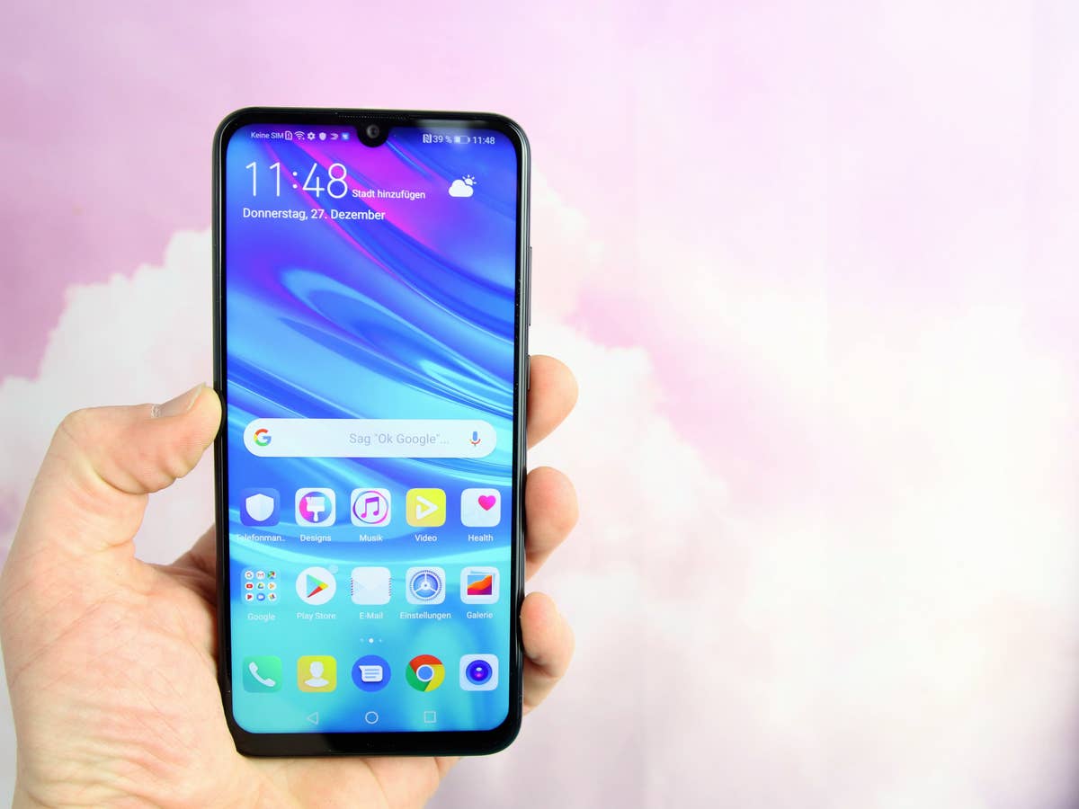 Huawei P smart 2019 in der Hand vor rosa Hintergrund