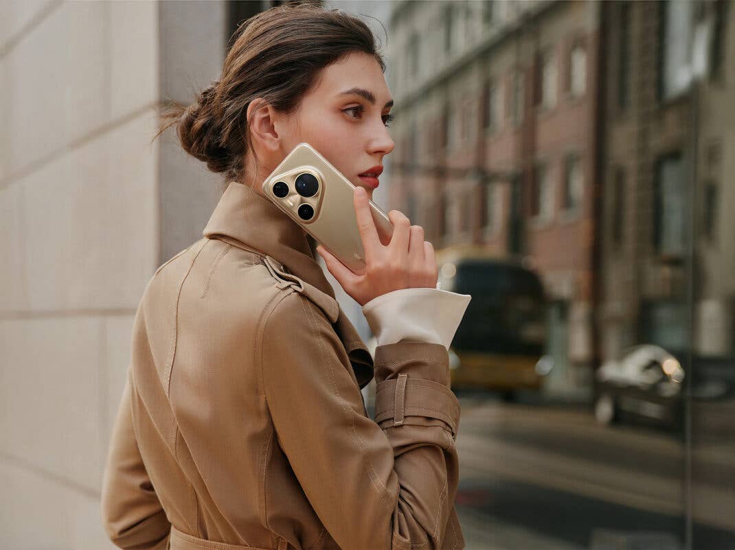 Eine Frau trägt das Huawei Pura 80 Ultra in den Händen und hält es ans Ohr.