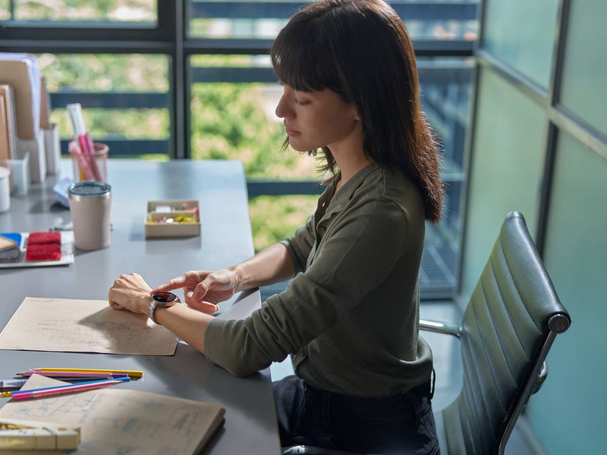 Eine Frau sitzt im Büro und trägt die Huawei Watch 5