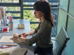 Eine Frau sitzt im Büro und trägt die Huawei Watch 5
