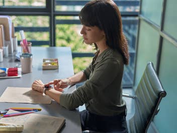 Eine Frau sitzt im Büro und trägt die Huawei Watch 5