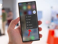 Eine Hand hält ein Smartphone, das ein Menü mit Optionen einschließlich 'Deinstallieren' anzeigt.