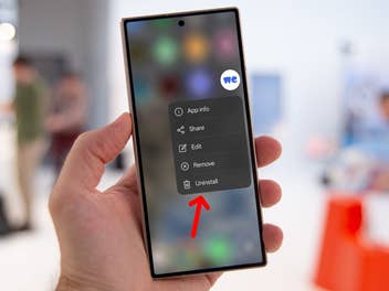 Eine Hand hält ein Smartphone, das ein Menü mit Optionen einschließlich 'Deinstallieren' anzeigt.