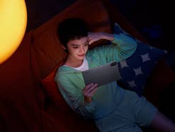 Eine Person, die sich auf einem Sofa entspannt und ein Xiaomi Redmi Pad 2 Tablet in einem schwach beleuchteten Raum verwendet.