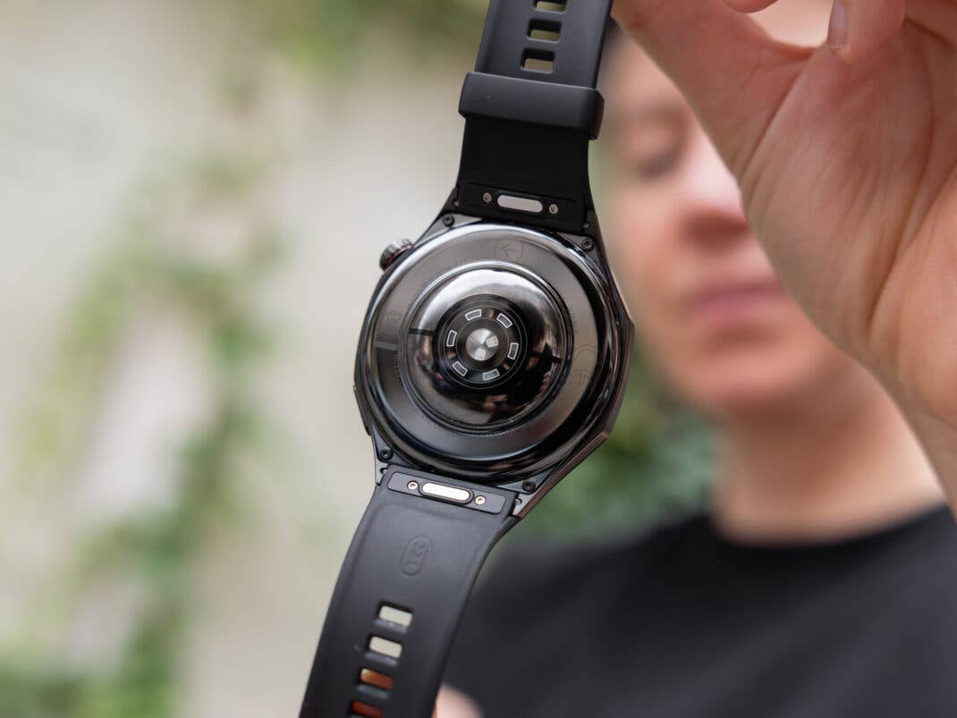 Eine Person hält die Rückansicht einer Huawei Watch GT 6 Pro mit schwarzem Armband.