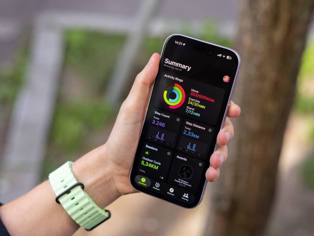 Eine Person hält ein Smartphone, das eine Aktivitätszusammenfassung von der Apple Watch zeigt.