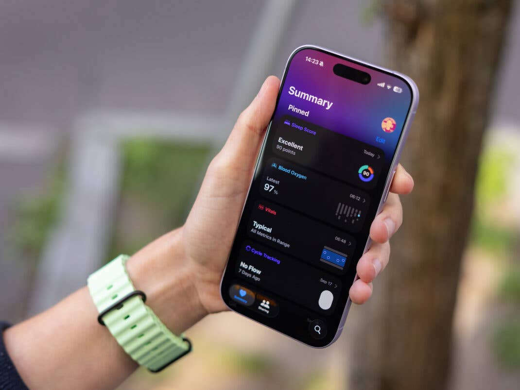 Eine Hand hält ein Smartphone, das Gesundheitszusammenfassungsdaten und eine Apple-Watch-Oberfläche zeigt.