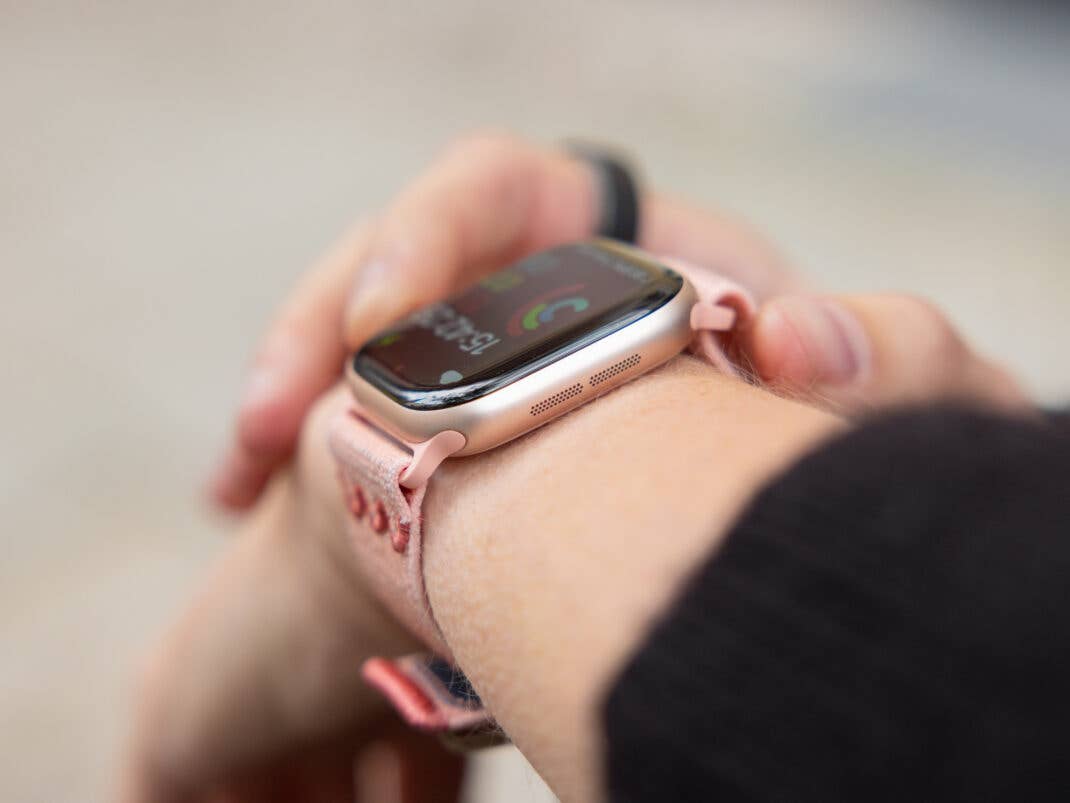 Eine Nahaufnahme einer Apple Watch am Handgelenk, die farbenfrohe Gesundheitsstatistiken anzeigt.