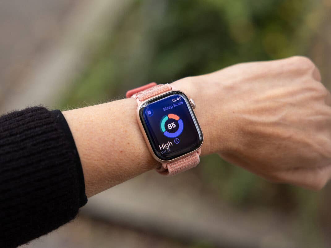 Eine Nahaufnahme einer Apple Watch, die eine Schlafbewertung von 85 am Handgelenk einer Person zeigt.