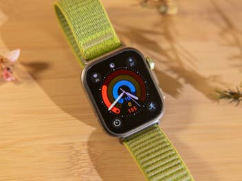 Eine Huawei Watch Fit 4 Pro auf einer Holzoberfläche, die Herzfrequenz- und Aktivitätsmetriken mit grünem Armband anzeigt.
