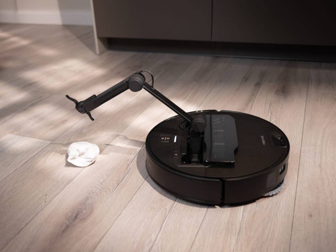 Ein schwarzer Saugroboter mit Greifarm