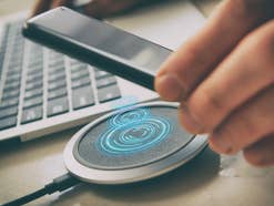 Ein Mann legt ein Smartphone auf ein induktives Ladegerät